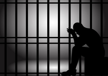 Man sitting behind prison bars