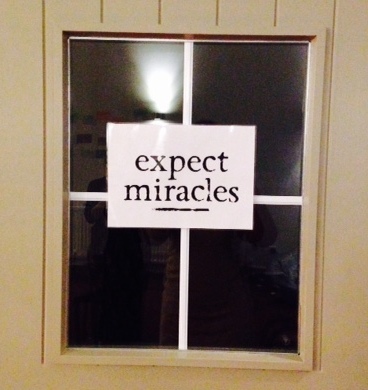 Window in a door with a sign saying 'Expect miracles'